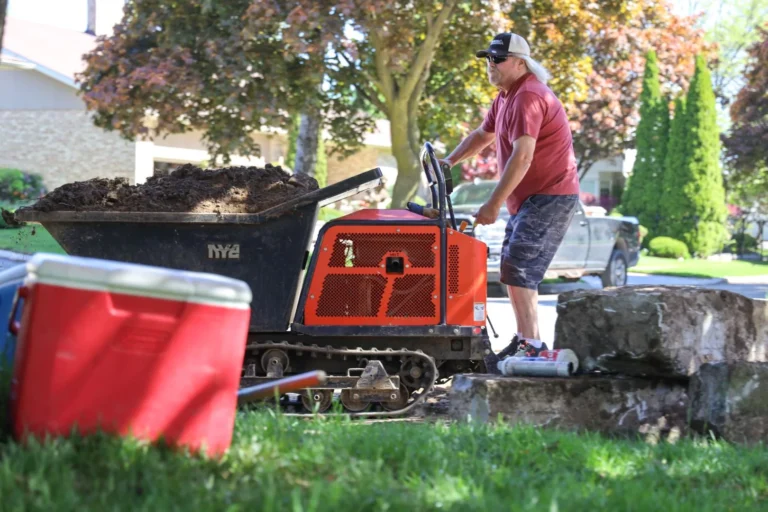 Worker operating Dingo compact track loader dumping soil during pool construction and landscaping project