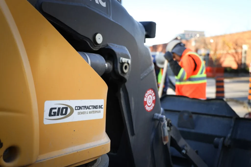Gio Contracting Inc. sewer and watermain construction crew with heavy equipment on city street excavation